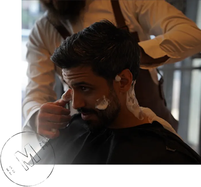 A barber at Monteman Barber carefully shaping a client's beard